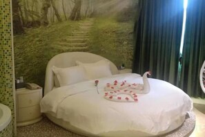 Een bed met decoratieve zwaan, nachtkastje en een muurschildering.