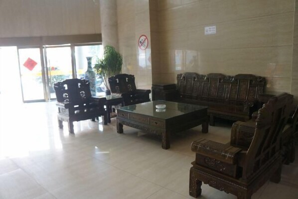 A lobby with a glass coffee table, wooden chairs, and sofas. - Yizhang Yiyuan Hotel (Yizhang)