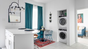 Una cocina compacta con una isla central, lavadora y comedor con sillas y mesa.