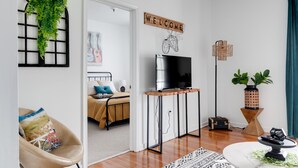 Una sala de estar moderna con televisor, un cartel de bienvenida y una decoración con bicicleta.