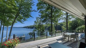 Une terrasse en bois, agréée de mobilier d’extérieur, qui offre une vue sur un lac et est entourée d’arbres.