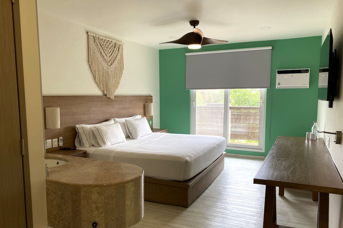 Ein Schlafzimmer mit einem Bett, einem runden Tisch, einem Deckenventilator und einem Fenster mit Klimaanlage.