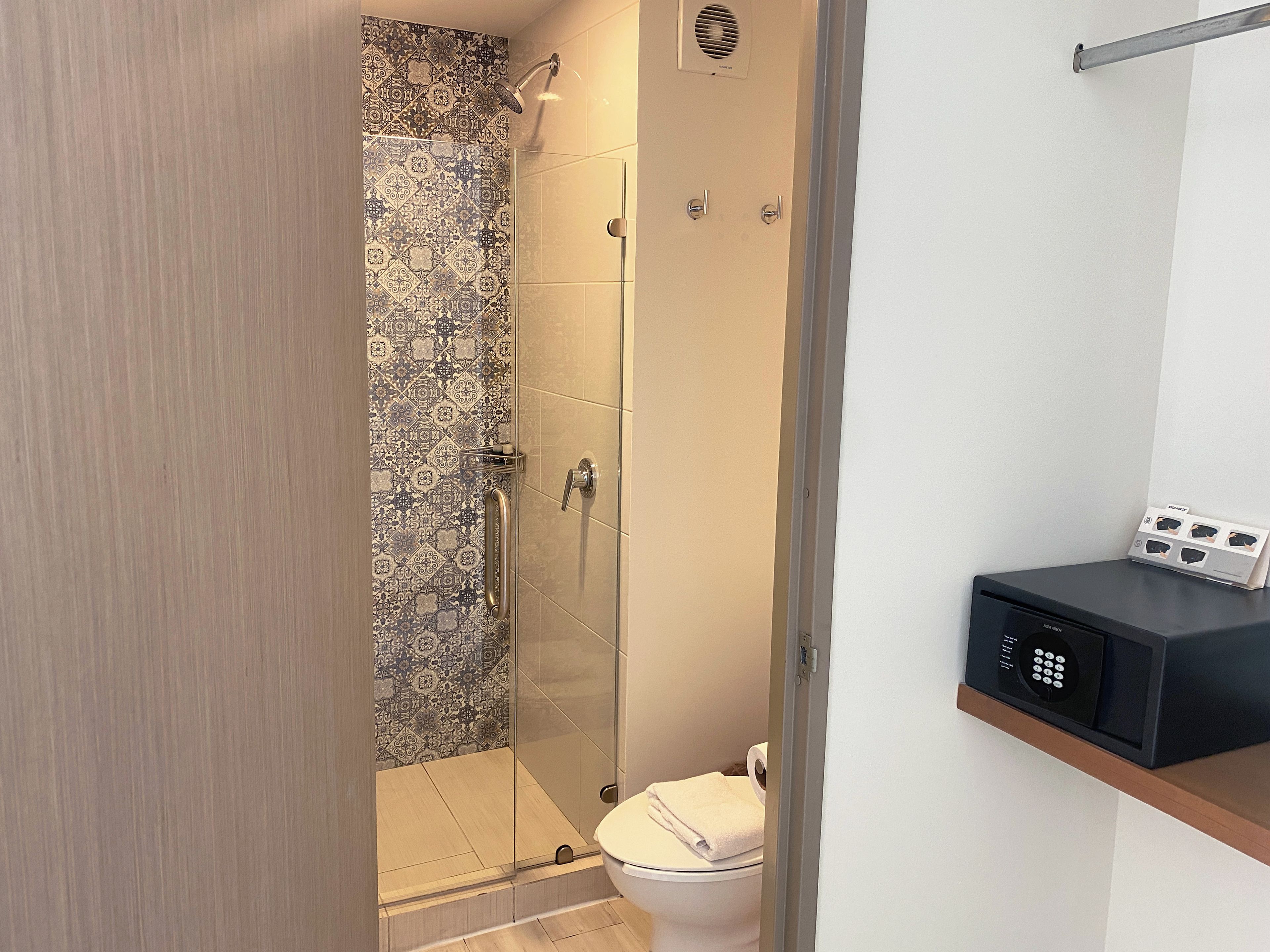 A bathroom with a shower, toilet, and a control panel on the wall.