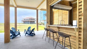 A covered outdoor area with wooden walls, a bar with stools, and Adirondack chairs. - BELLE VUE- Pristine Bay Views - Community Pool (Galveston)