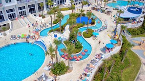 Relax by the pool surrounded by lush greenery and palm trees, with multiple pools and water features to enjoy.