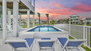 A pool area with lounge chairs, a clear view of the sunset, and a white fence surrounding the property. - Seabatical! Home with private pool in Pointe West (Galveston)