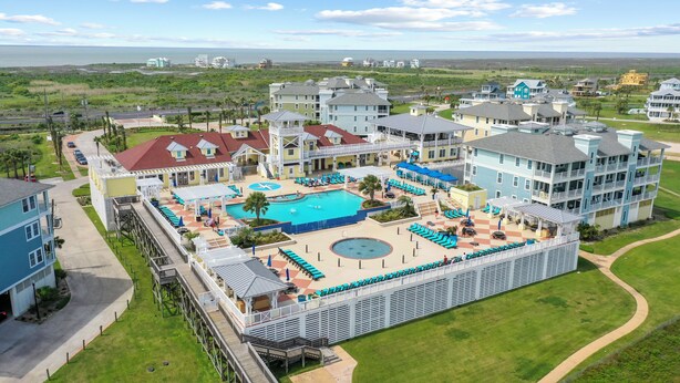 A resort with a central pool, multiple buildings, and a view of the ocean. - Seabatical! Home with private pool in Pointe West (Galveston)