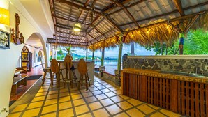Un restaurante con techo de paja, muebles de madera y una barra de piedra.