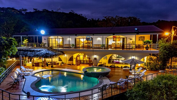 Un resort con piscina, sillas de descanso y zona de restaurante.