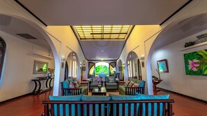 Un hallo espacioso con una zona de estar central, tragaluces y vistas a un jardín exuberante a través de las ventanas.