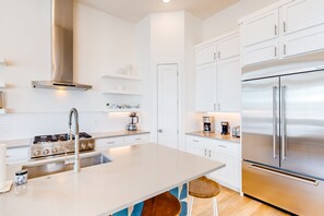 Enjoy cooking in this well-equipped kitchen with a central island, gas stove, and stainless steel refrigerator.