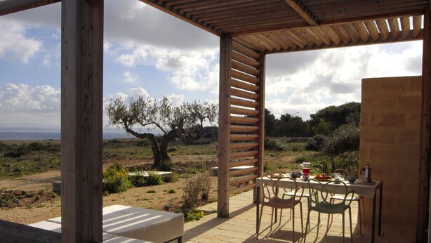 Un espacio de estar al aire libre cubierto con una mesa, sillas y vistas al paisaje.