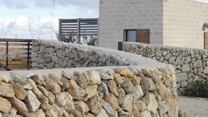 Un muro de piedra y un edificio moderno con una puerta de madera y una ventana.