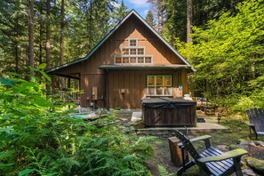 A wooden cabin with a deck, a hot tub, and outdoor seating. - Cozy Cascade Cabin. Relaxing Hot Tub, Spacious and Creek Nearby (Rhododendron)