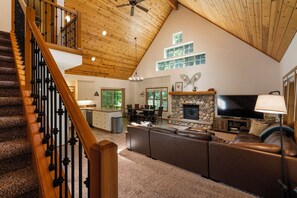 A spacious living area with a fireplace, a large TV, and a cozy seating area. - Cozy Cascade Cabin. Relaxing Hot Tub, Spacious and Creek Nearby (Rhododendron)