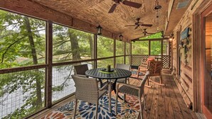 Un espacio al aire libre cubierto con una mesa, sillas, ventanas amplias y ventiladores de techo.
