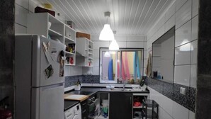 A compact kitchen with a washing machine, a refrigerator, and a sink. - House (Ribeira Grande)