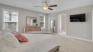 A bedroom with a bed, a ceiling fan, a dresser, a mirror, and a TV mounted on the wall. - Spacious 4 BD Golf Getaway with Game Room! (Aberdeen)
