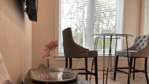 Un saló modern amb una taula de fusta fosca, dues cadires tapissades, una taula de centre de vidre i una orquídia en test.