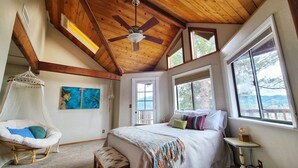 A bedroom with a bed, a hanging chair, a ceiling fan, and large windows. - Cozy & Quiet 2 bdrm private Treehouse getaway with Amazing Views minutes from UO (Eugene)