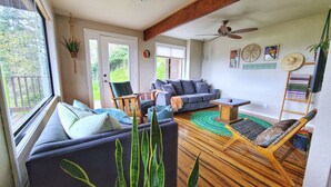 A cozy living room with a sofa, chairs, a coffee table, and a wooden floor. There is a ceiling fan, a window with blinds, and a door leading outside. - Cozy & Quiet 2 bdrm private Treehouse getaway with Amazing Views minutes from UO (Eugene)