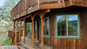 A wooden cabin with a deck, large windows, and a balcony. - Cozy & Quiet 2 bdrm private Treehouse getaway with Amazing Views minutes from UO (Eugene)
