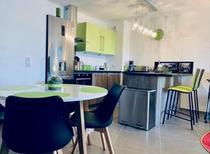 A modern kitchen with a dining area, stainless steel appliances, and a green accent wall.