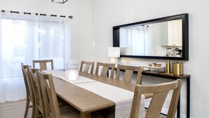 A dining area with a long wooden table, six chairs, a patterned runner, and a modern pendant light. - Beautiful 5-Bdrm Vacation Home W/Heated Pool ! (Scottsdale)