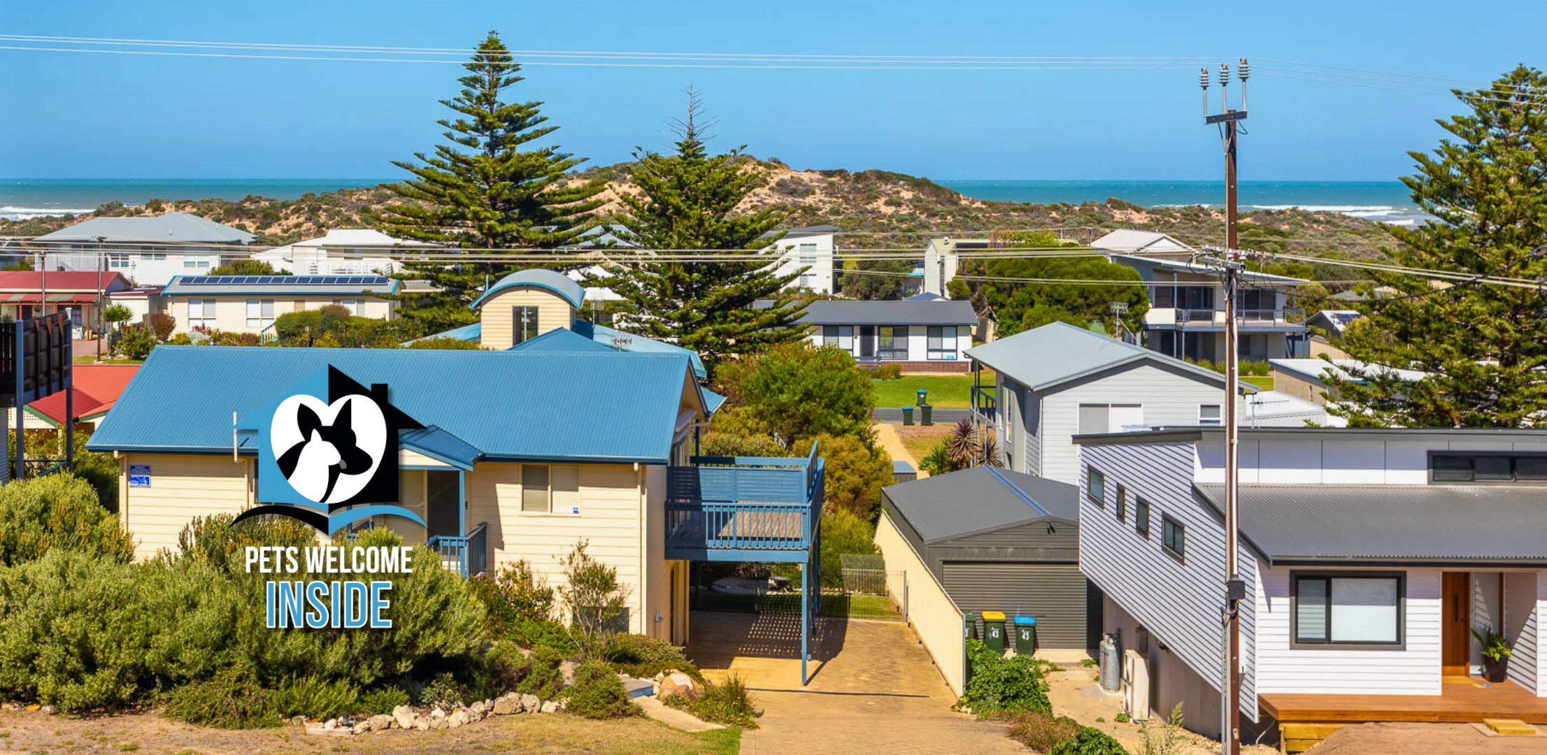 A residential area with houses, a clear sky, and a view of the sea.