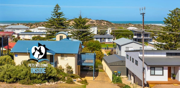 A residential area with houses, a clear sky, and a view of the sea.