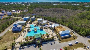 Ett flygbildsfoto av ett semesterområde med en stor swimmingpool, flera byggnader och utsikt över havet.