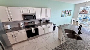 A modern kitchen with white cabinets, stainless steel appliances, and a granite countertop.
