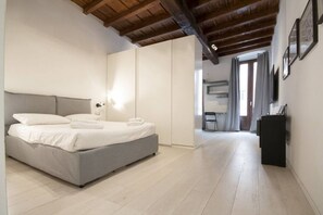 A bedroom with a bed, a wardrobe, a desk, and a chair.