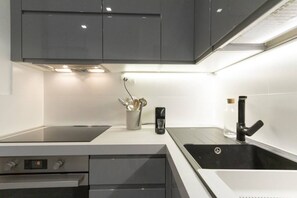 A modern kitchen with a built-in oven, a stovetop, a sink, and a coffee maker.