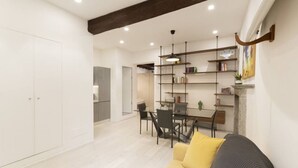 Ein modernes Wohnzimmer mit einer Couch, einem Esstisch, Stühlen und einem Bücherregal.