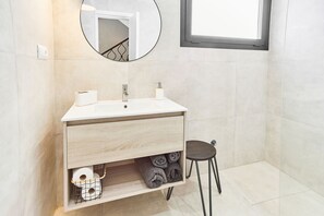 Un baño moderno con un lavabo blanco, un espejo y una ventana.