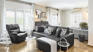 A modern living room with a black leather sofa, a grey armchair, and a small round table. There is a potted plant and a white floor lamp. - VILLA IN FUENGIROLA CENTER. NEW LUXURY POOL! (Fuengirola)
