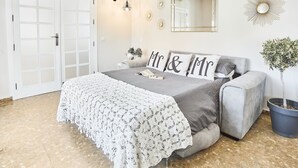 A bedroom with a bed, a grey sofa, a white lace bedspread, a mirror, and a potted plant. - VILLA IN FUENGIROLA CENTER. NEW LUXURY POOL! (Fuengirola)