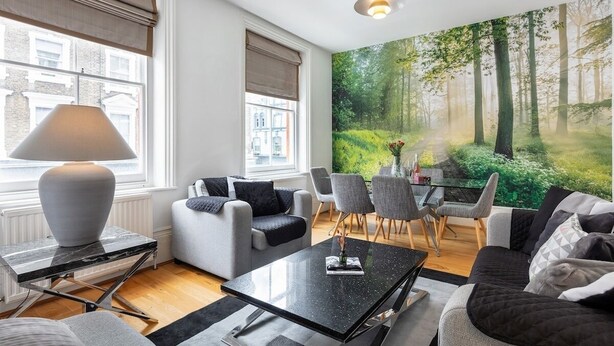 Un salon moderne doté d’une grande fenêtre, d’un canapé, d’une table basse et d’un coin repas.