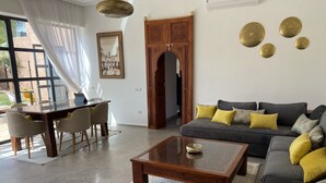 Un saló amb un sofà, una taula de centre i una zona de menjador amb cadires.