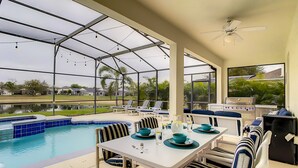 Un espace extérieur abrité comprenant une piscine, une table à manger, des chaises et un barbecue.