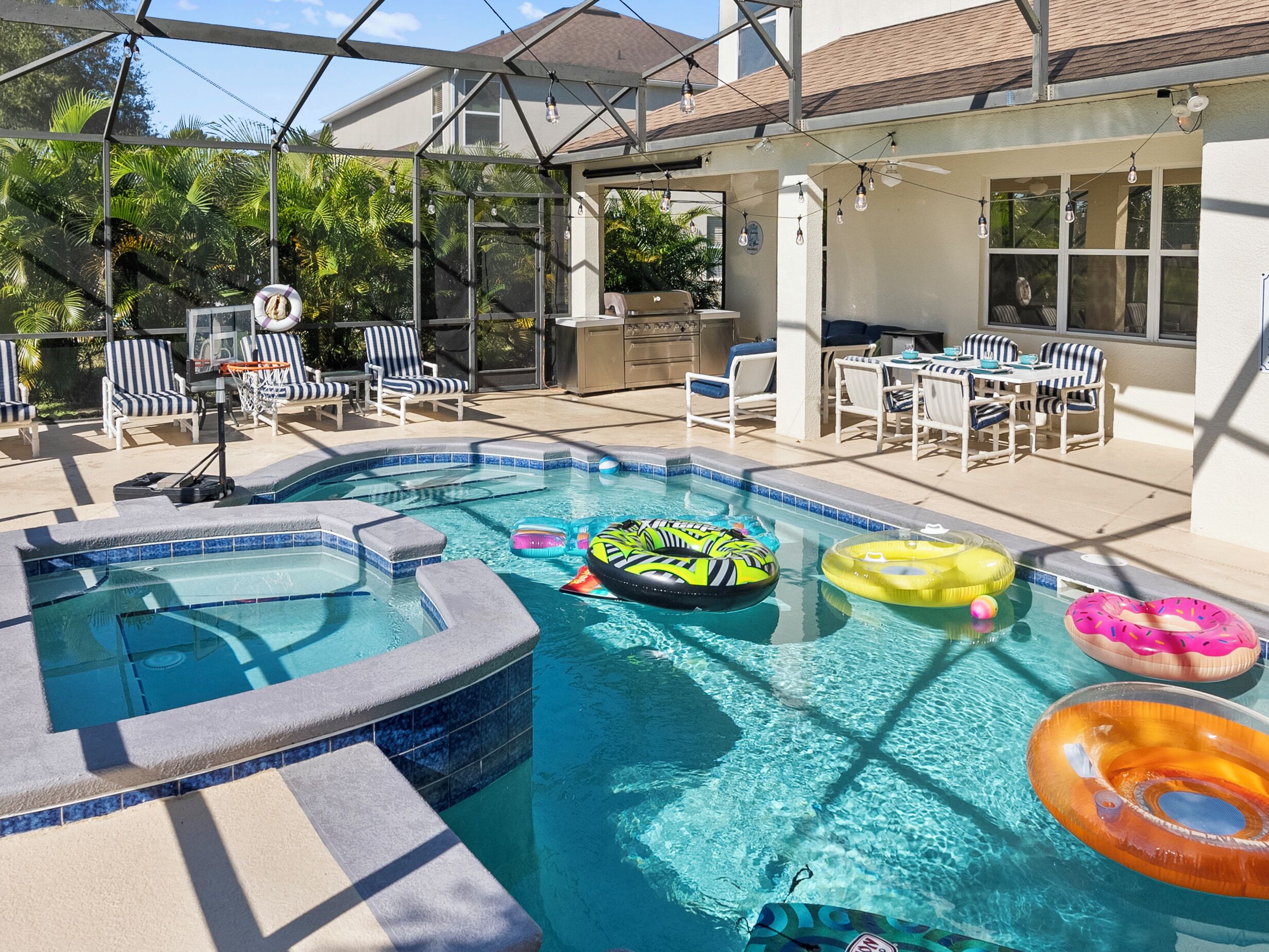 A swimming pool with a hot tub, surrounded by lounge chairs and a dining area.