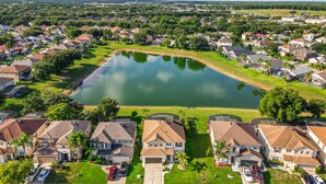 Un quartier résidentiel avec des maisons, un étang central et un ciel dégagé.