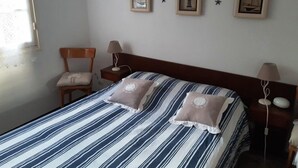 Un dormitori ben organitzat amb un edredó a ratlles, dues làmpades de nit i una cadira.