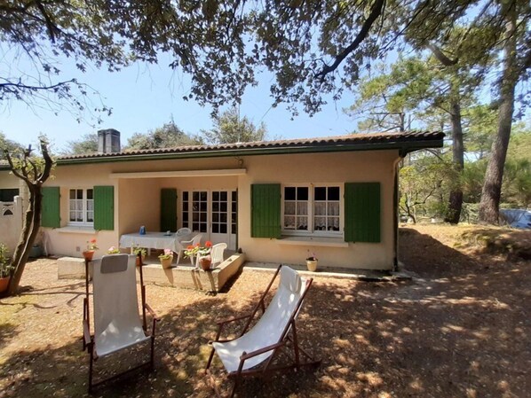 A small house with a patio, green shutters, and outdoor seating.