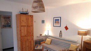 Una habitació acollidora amb un armari de fusta, un llit amb roba de llit estriada, una taula amb un ram i una làmpada penjant.