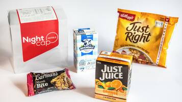 A variety of food items including a carton of Devondale milk, a bag of Kellogg's Just Right snacks, a box of Just Juice orange juice, and a package of Carman's Muesli Bite.