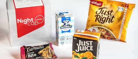 Ett urval av livsmedel, inklusive en förpackning Devondale-mjölk, en påse Kellogg's Just Right-snacks, en kartong Just Juice-apelsinjuice och en förpackning Carman's Muesli Bite.