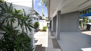 A modern outdoor corridor with a concrete floor, white walls, and a blue awning. - Apartments at Mission Beach (Mission Beach)