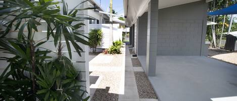 A modern outdoor corridor with a concrete floor, white walls, and a blue awning.